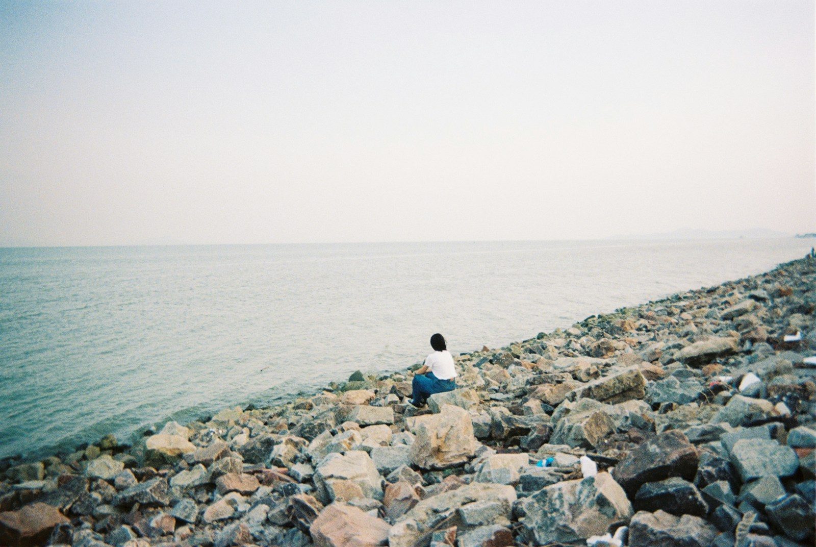Person sitting on rocks by the sea